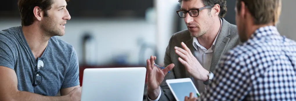 group of men talking with laptops 